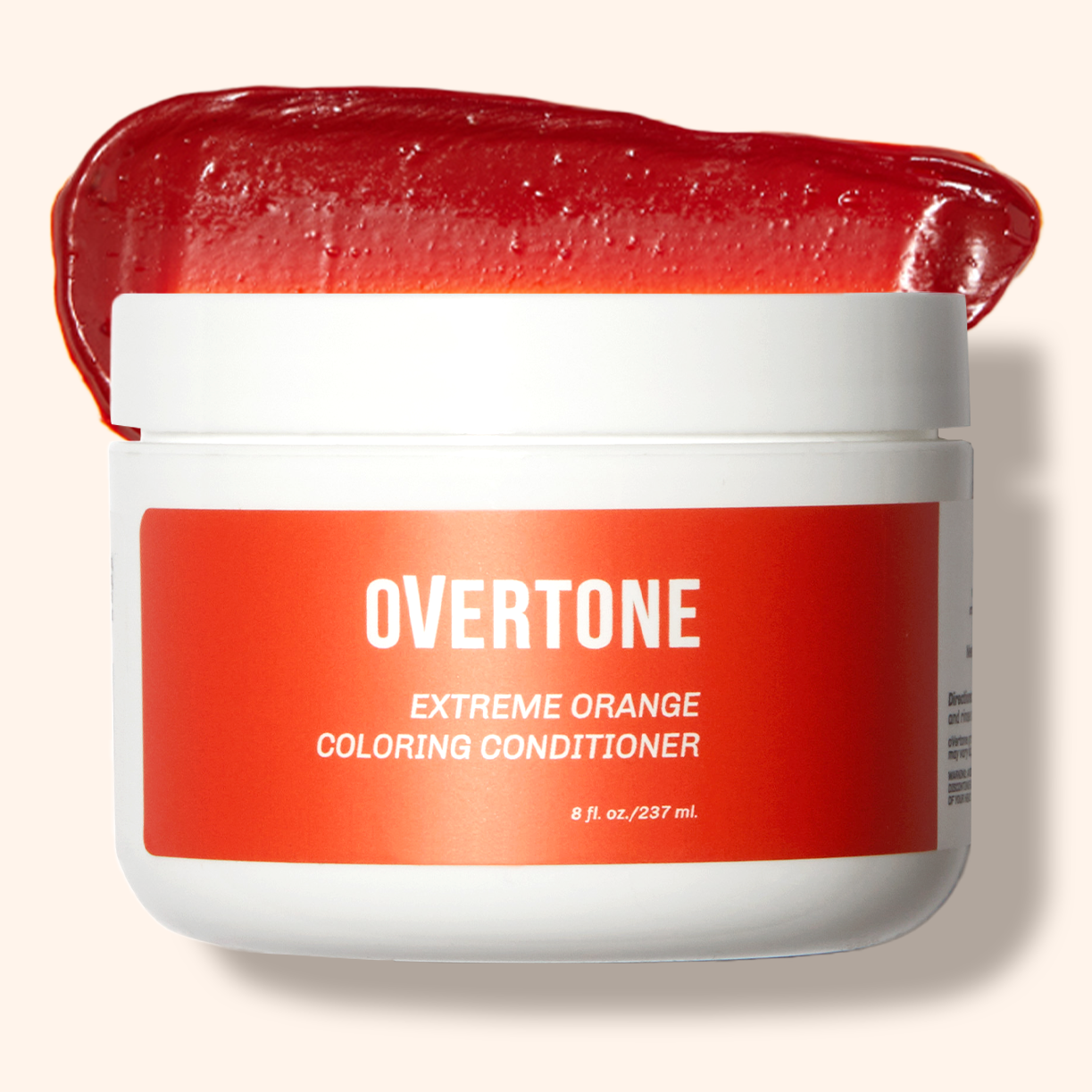 A container of OVERTONE Extreme Orange Coloring Conditioner with a spoonful of the product scooped out to show the texture.