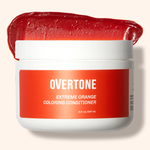 A container of OVERTONE Extreme Orange Coloring Conditioner with a spoonful of the product scooped out to show the texture.