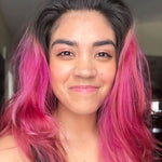 person with dark roots and vibrant magenta hair color on medium length, pre-lightened hair