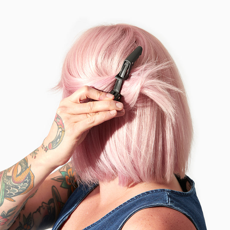 person with pastel pink hair using black crocodile hair clip
