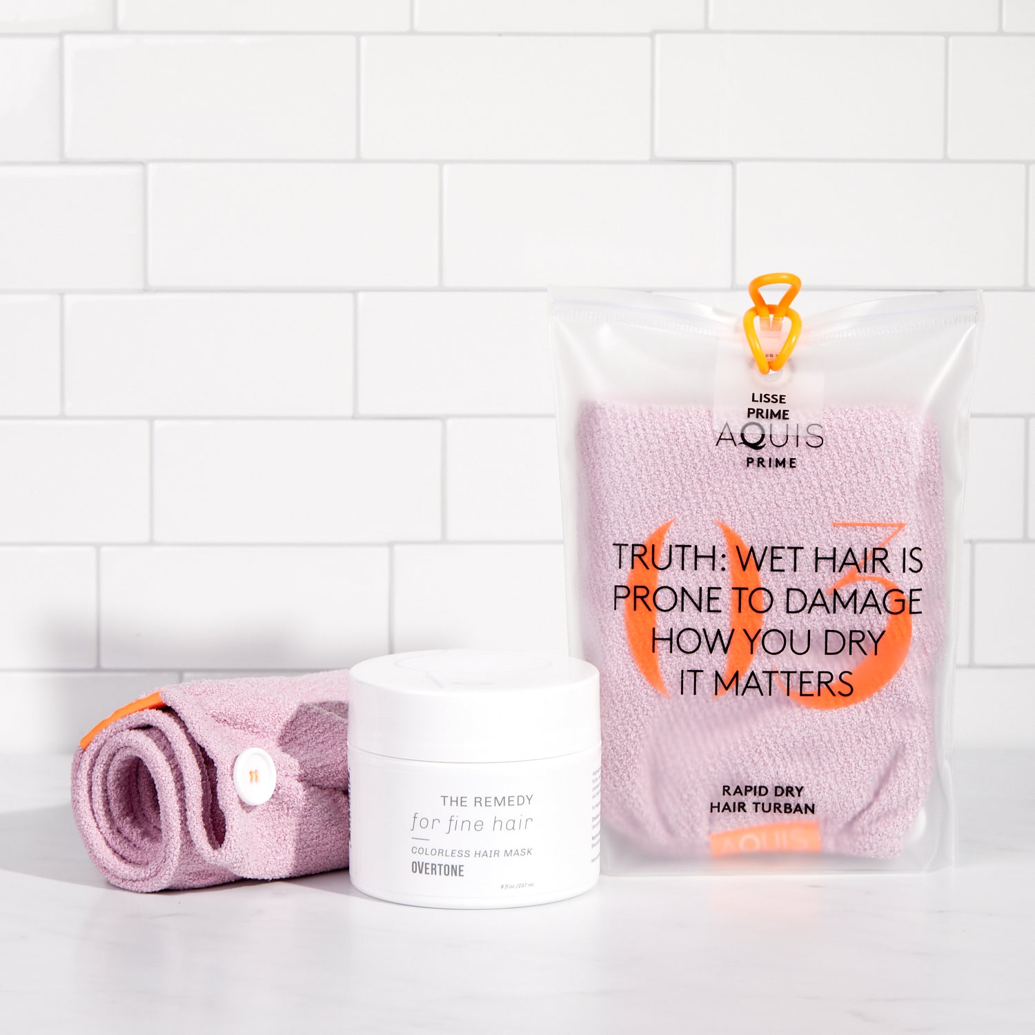 light pink towel in bag and remedy hair mask for fine hair on shower shelf