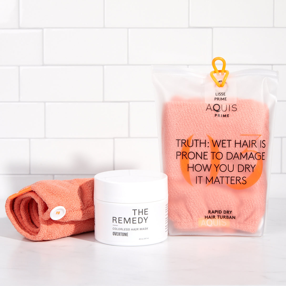 light orange towel in bag and remedy hair mask on shower shelf