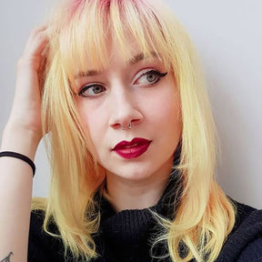 person with medium length light yellow hair color with bangs and light pink roots, wearing red lipstick