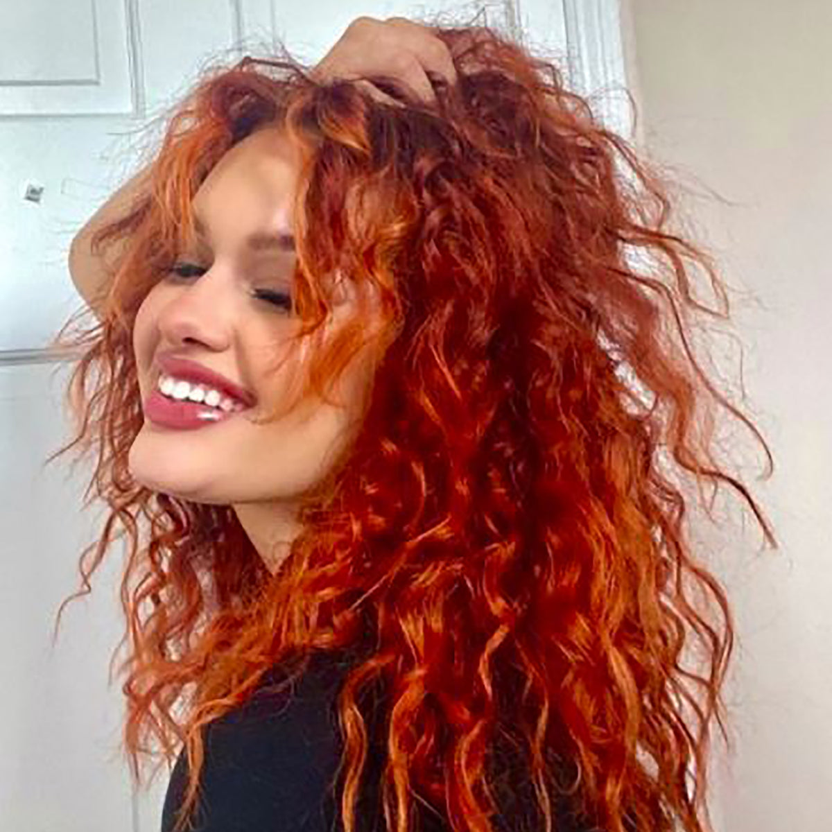 bright orange hair color on person with long, curly pre-lightened hair