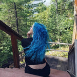 person with long turquoise hair color on pre-lightened curly hair