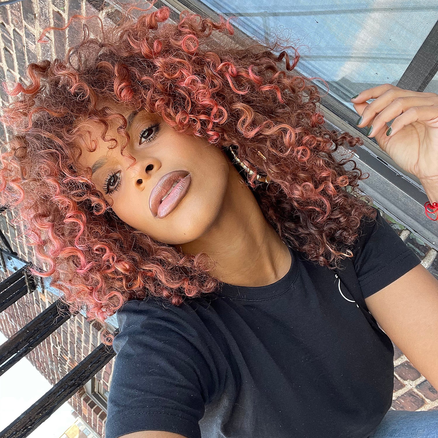 person with curly rose gold hair color on pre-lightened shoulder length hair