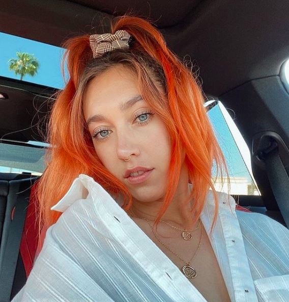 orange hair color on person with long pre-lightened hair in a high pony tail with long bangs