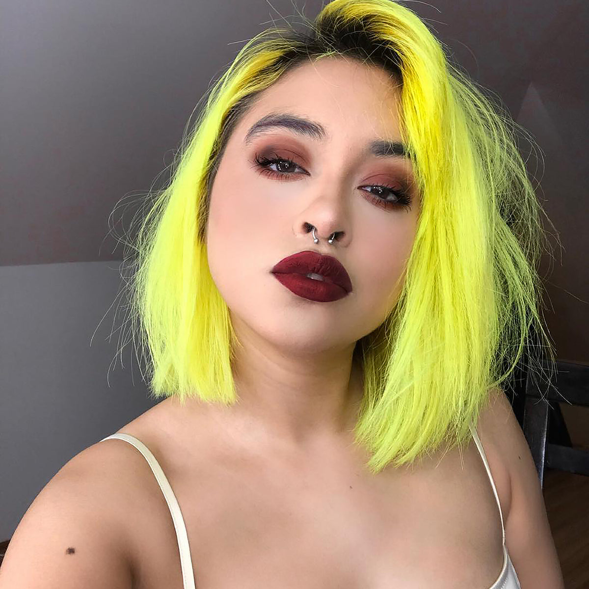 person with dark roots and short pre-lightened neon yellow hair with dark red lipstick